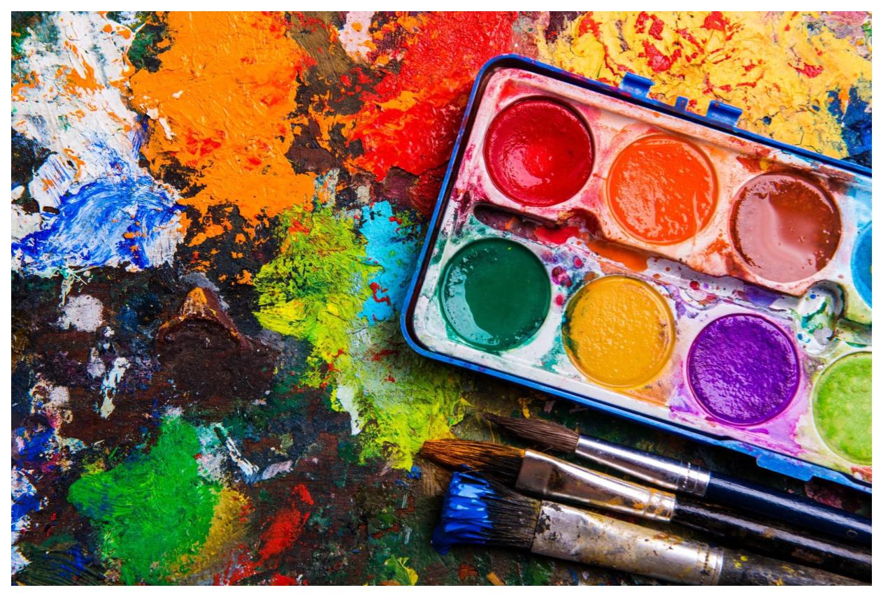 paint palette with brushes and paint splatter on table