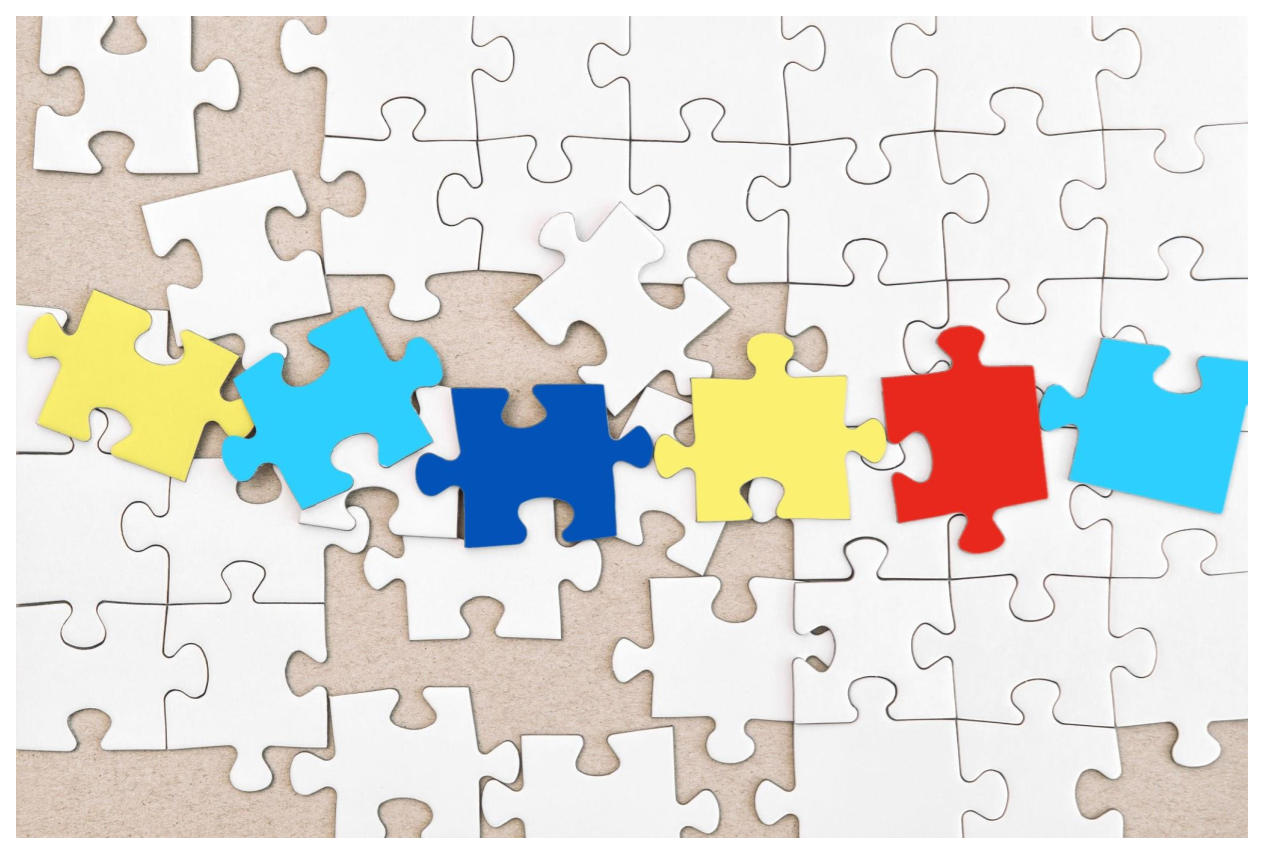 white puzzle pieces with yellow, blue and red puzzle pieces on top