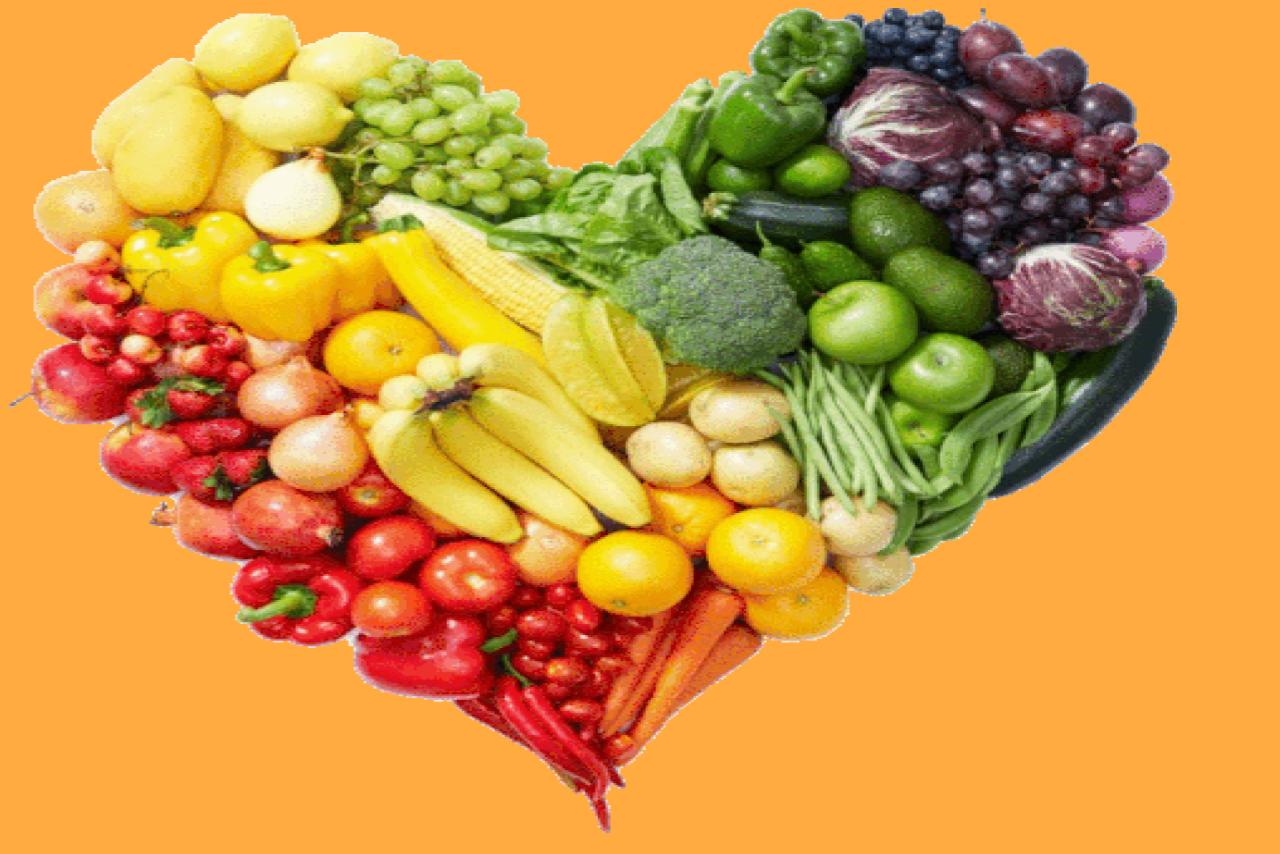 heart shaped layout of vegetables in fruits in red, yellow, green and purple against an orange background